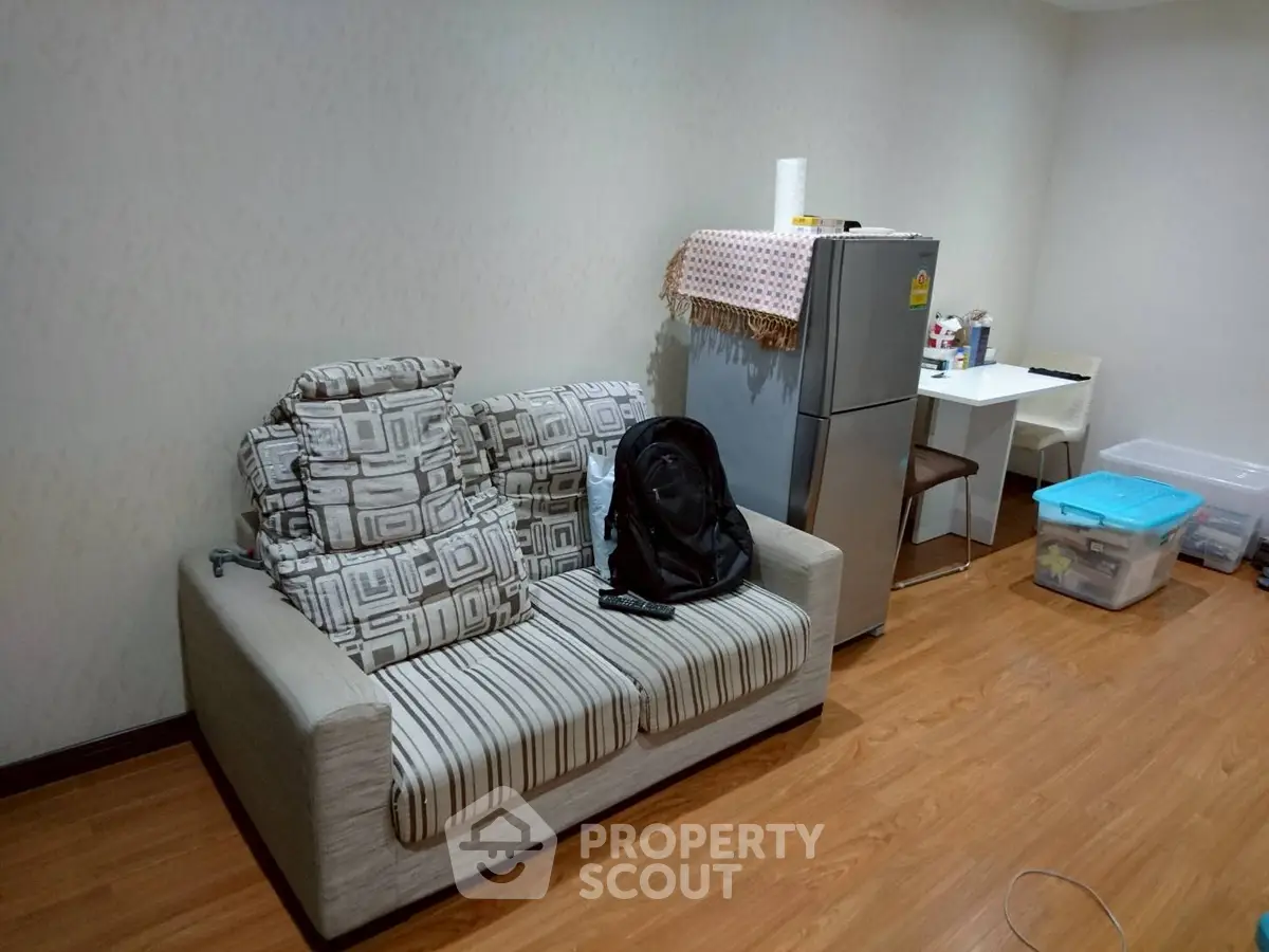 Cozy living room with sofa and fridge, perfect for small apartments.