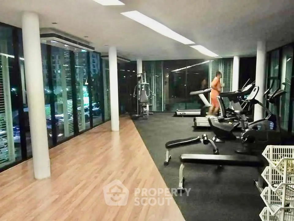 Modern gym with large windows and fitness equipment in upscale residential building.