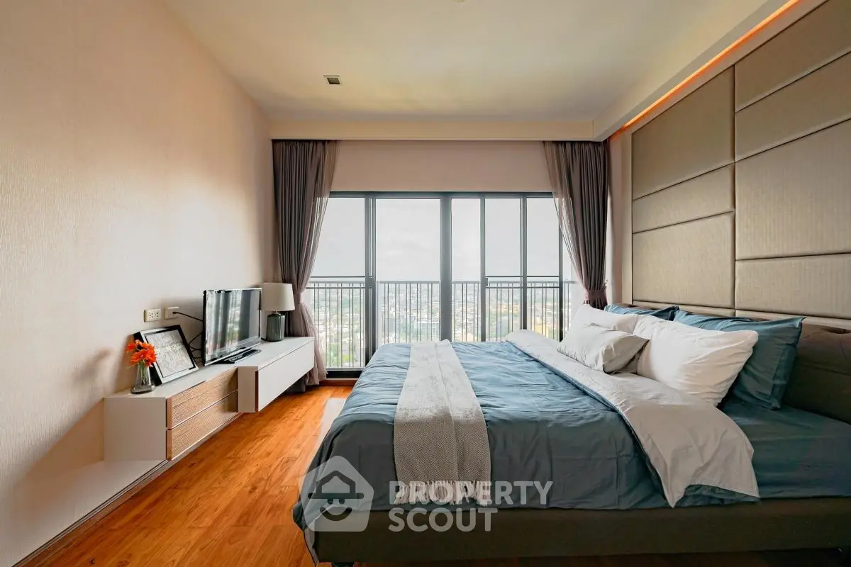 Luxurious bedroom with large windows and modern decor in high-rise apartment.