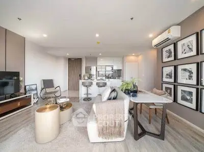 Modern open-plan living room with stylish decor and kitchen area, featuring contemporary furniture and artwork.