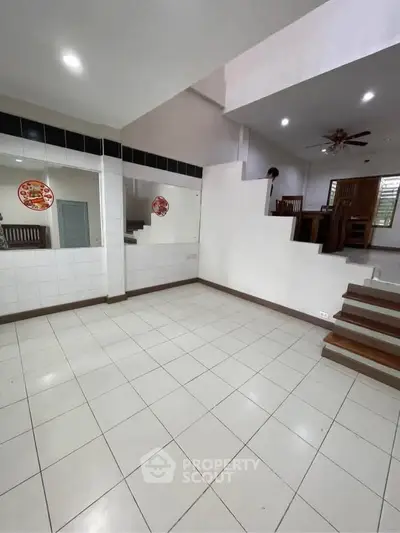 Spacious open-plan living area with tiled flooring and modern staircase design.