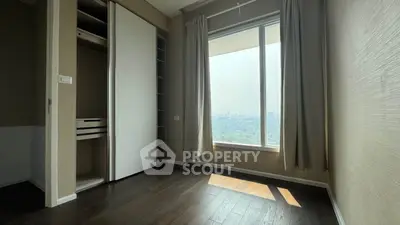 Bright bedroom with large window offering stunning city view and built-in closet, perfect for urban living.