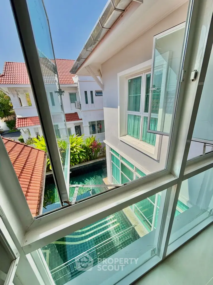 Stunning view from window overlooking modern villa with pool and lush greenery