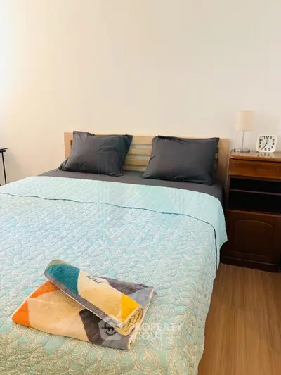 Cozy bedroom with stylish bedding and wooden nightstand, perfect for relaxation and comfort.