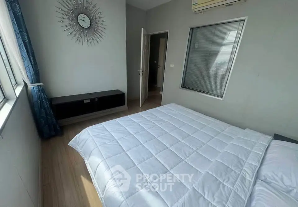 Spacious bedroom with modern decor and large window for natural light.