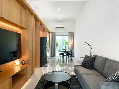 Modern living room with sleek furniture and open layout leading to dining area.
