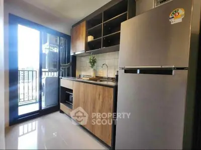 Modern kitchen with sleek design, stainless steel fridge, and open balcony view.