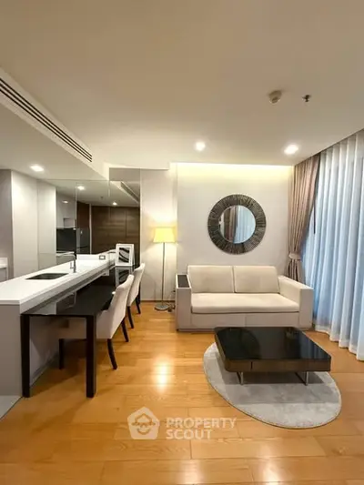 Modern living room with open kitchen, stylish decor, and cozy ambiance.