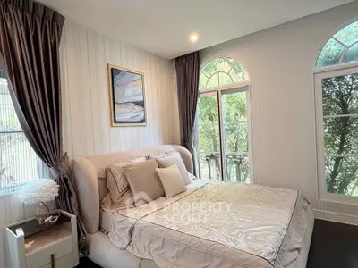 Elegant bedroom with large windows and stylish decor, offering a serene view of lush greenery.