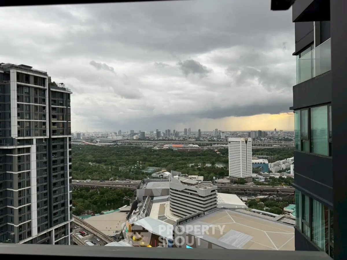 Stunning cityscape view from high-rise balcony with expansive skyline and lush greenery.