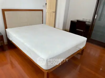 Spacious bedroom with wooden flooring and modern furniture