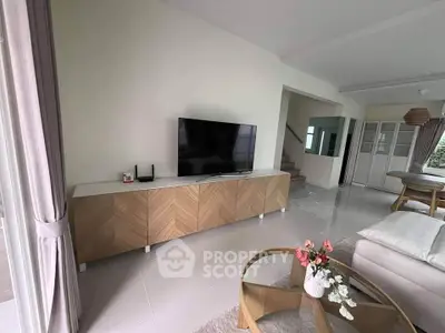 Modern living room with stylish furniture and large TV, featuring elegant decor and natural light.