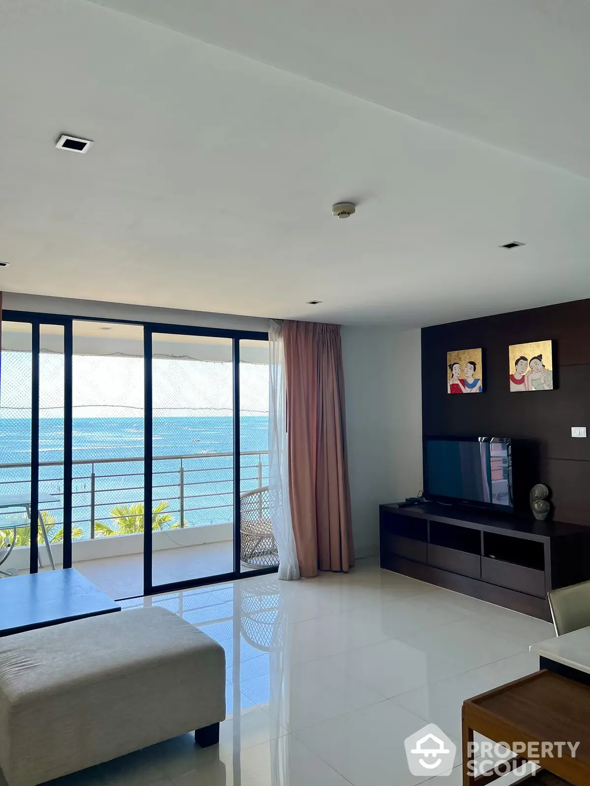 Spacious living room with floor-to-ceiling windows offering an unobstructed ocean view, modern furnishings, and direct balcony access for a serene living experience.