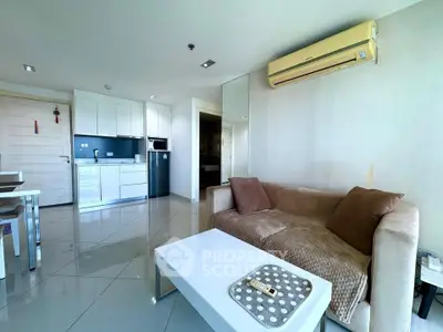 Modern living room with sleek kitchen, featuring a cozy sofa and air conditioning.