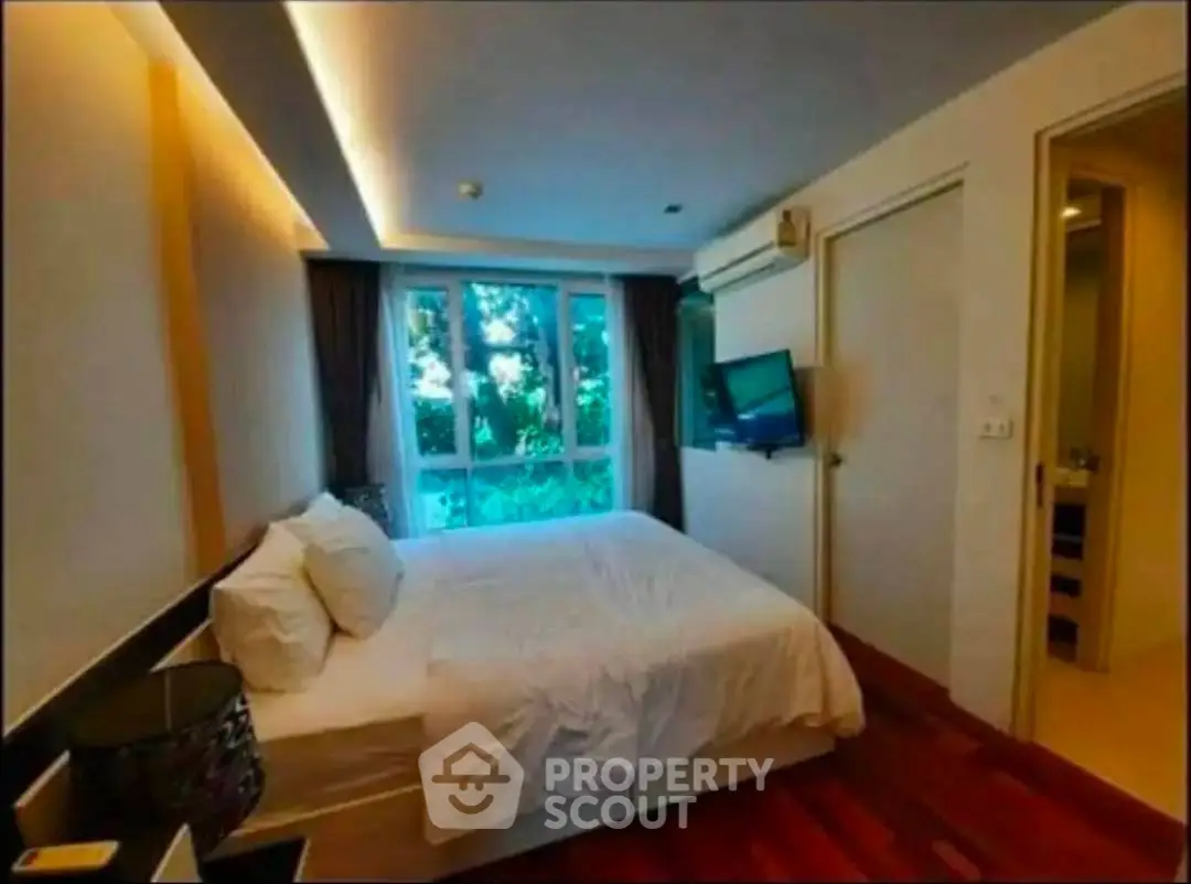 Cozy bedroom with modern design and large window offering natural light and garden view.