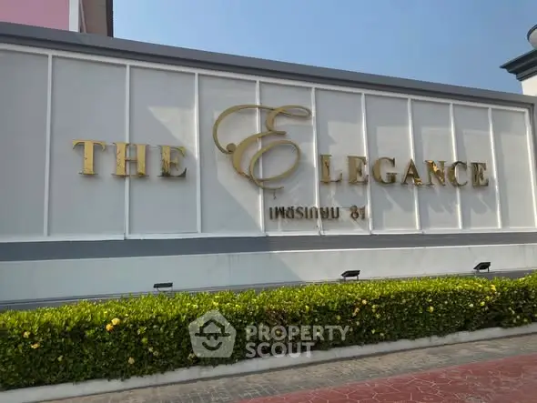 Elegant building entrance with stylish signage and lush greenery.