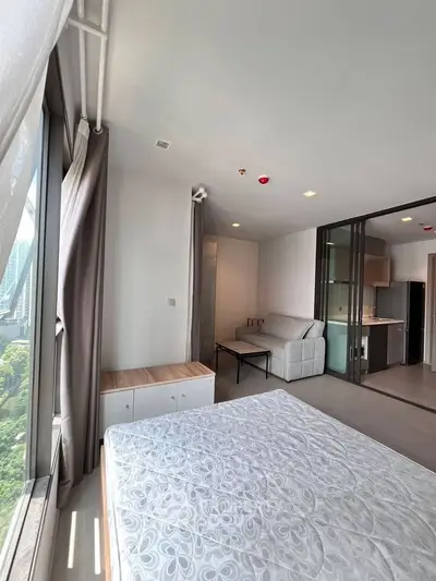 Modern studio apartment with large windows and open kitchen layout, offering a bright and airy living space.