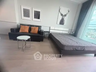 Modern studio apartment with stylish decor and city view, featuring a sleek black sofa and minimalist bed.
