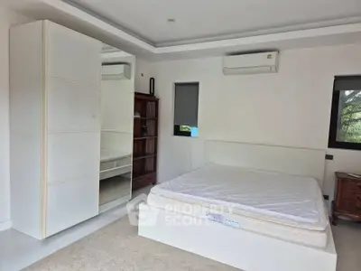 Spacious bedroom with modern furnishings and air conditioning unit