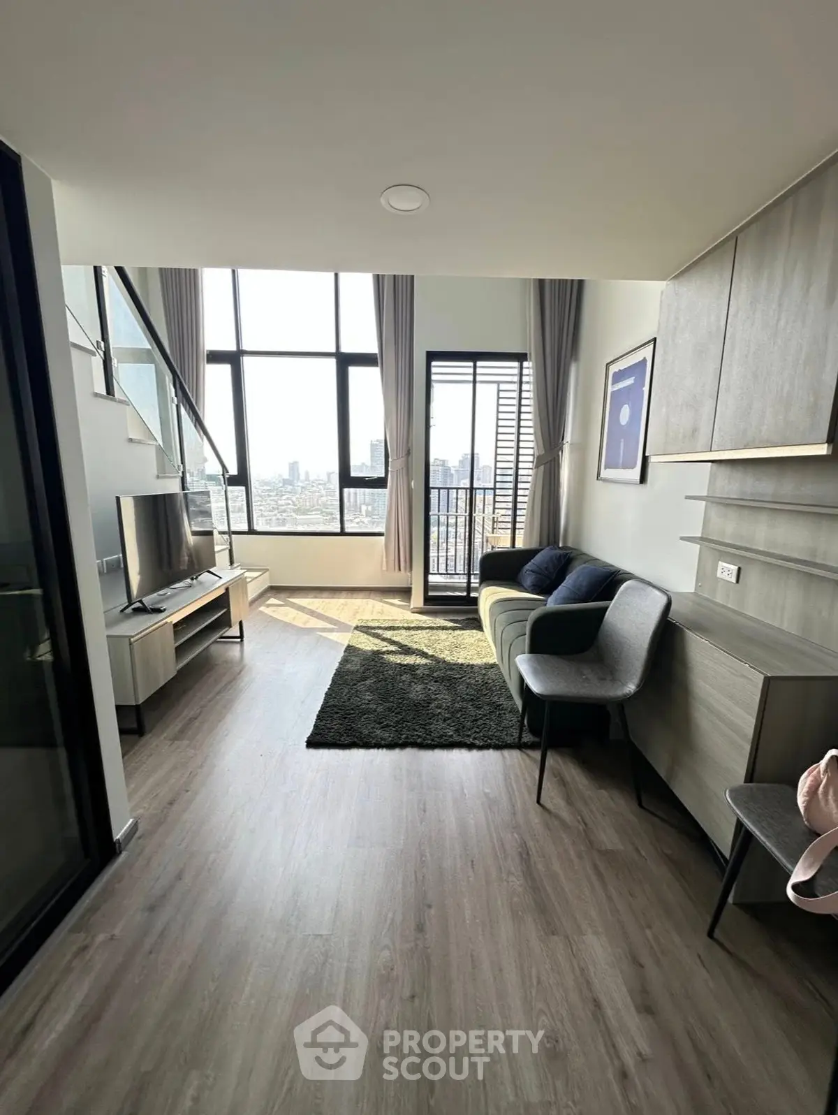 Modern living room with high ceilings and city view, featuring stylish furniture and large windows.