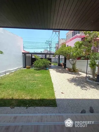 Spacious garden view with paved walkway and lush greenery in a modern residential area.