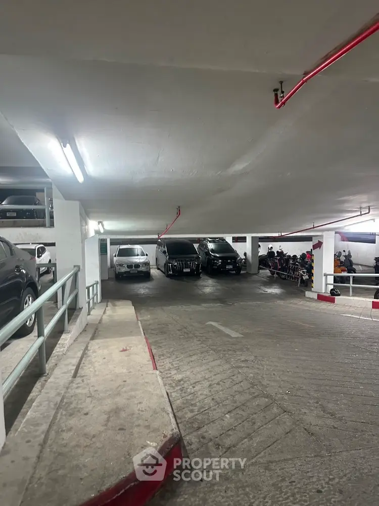 Spacious underground parking area with multiple vehicles and ample lighting.