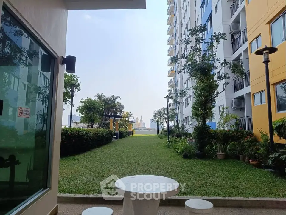 Charming garden view from modern apartment complex with lush greenery and city skyline backdrop.