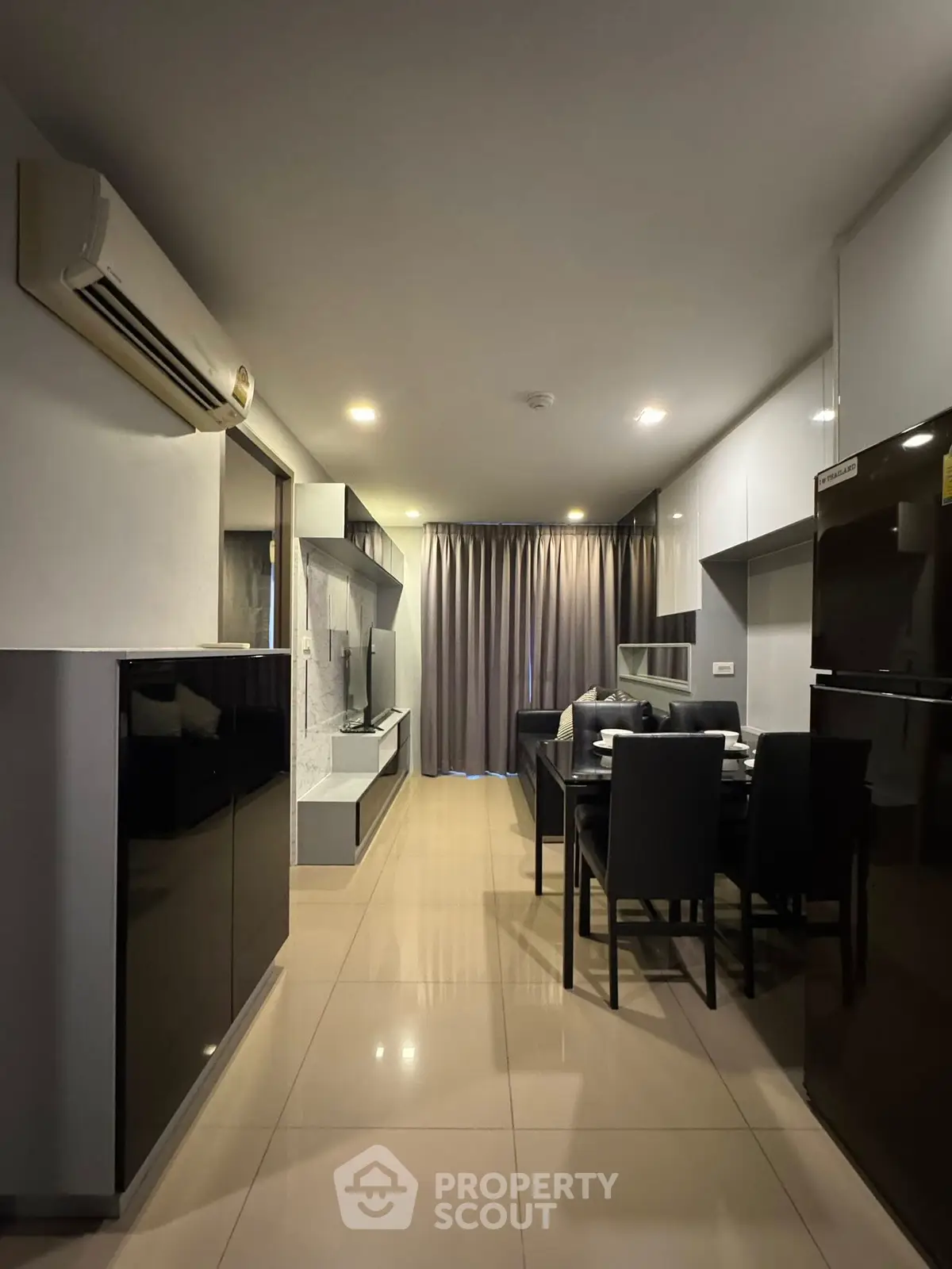 Modern living room with dining area and sleek black furniture, featuring air conditioning and elegant lighting.
