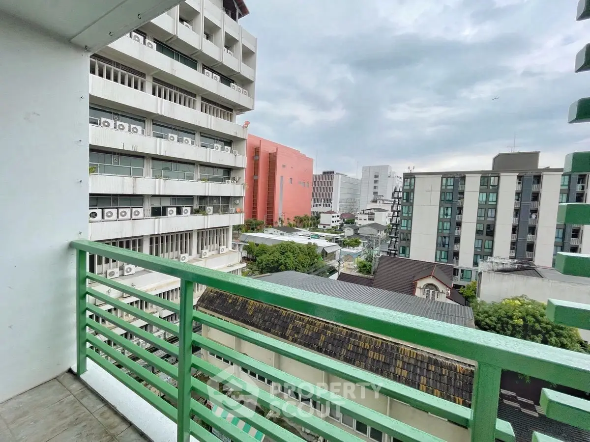 Scenic urban balcony view with modern buildings and overcast sky.