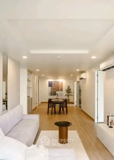 Spacious modern living room with elegant decor and dining area, featuring sleek air conditioning units.