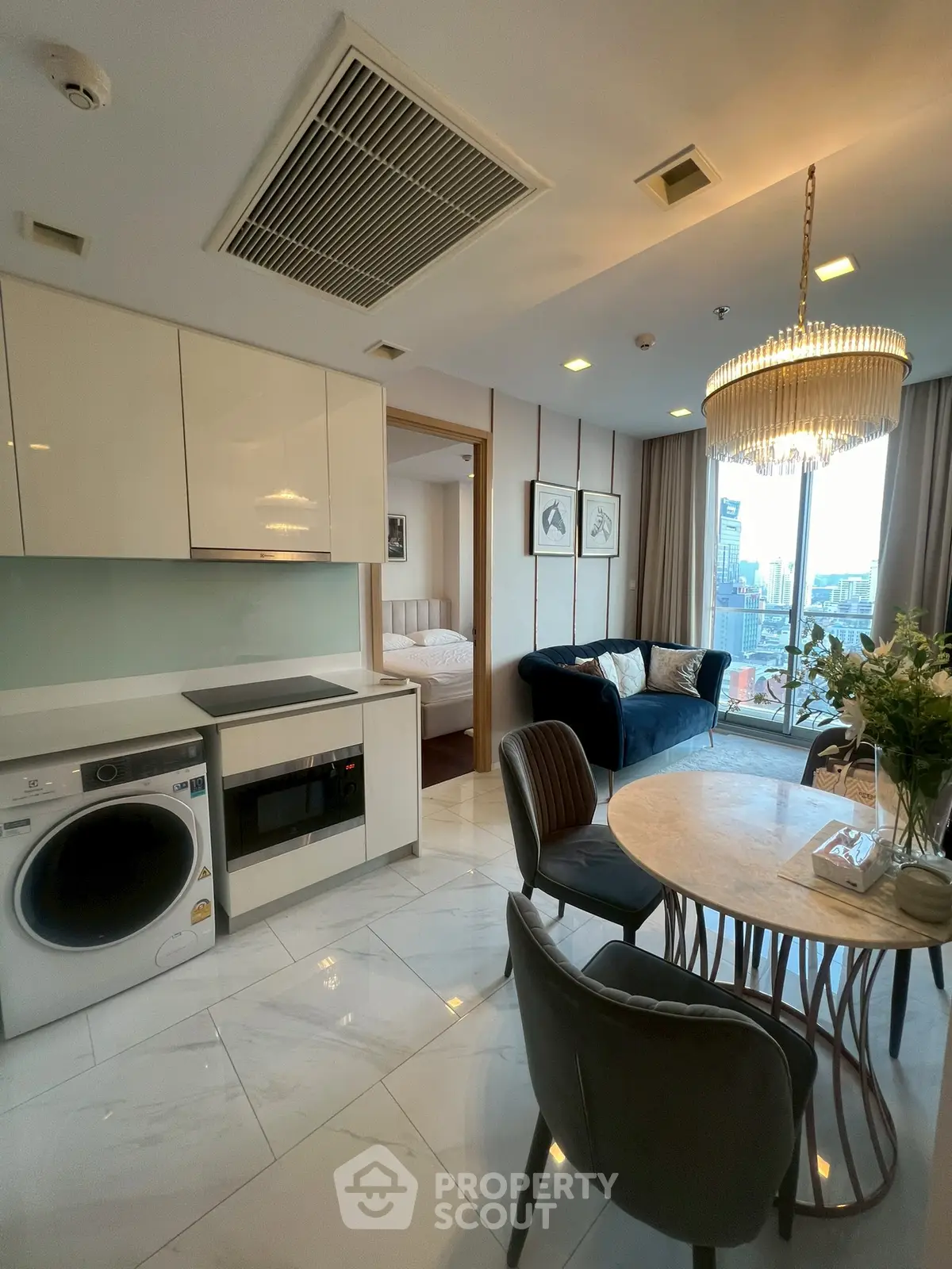 Modern open-layout living room with kitchen, dining area, and city view from large window.