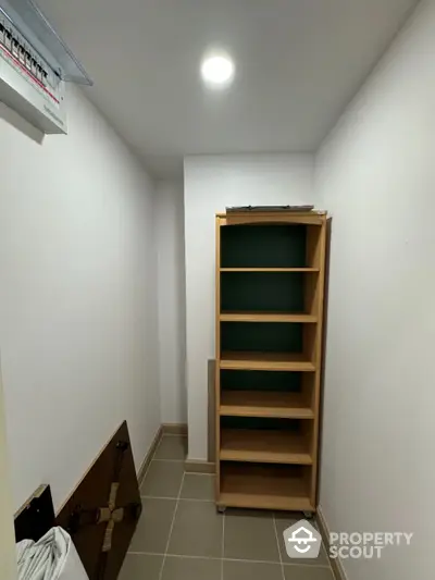 Compact storage room with wooden shelving and tiled flooring