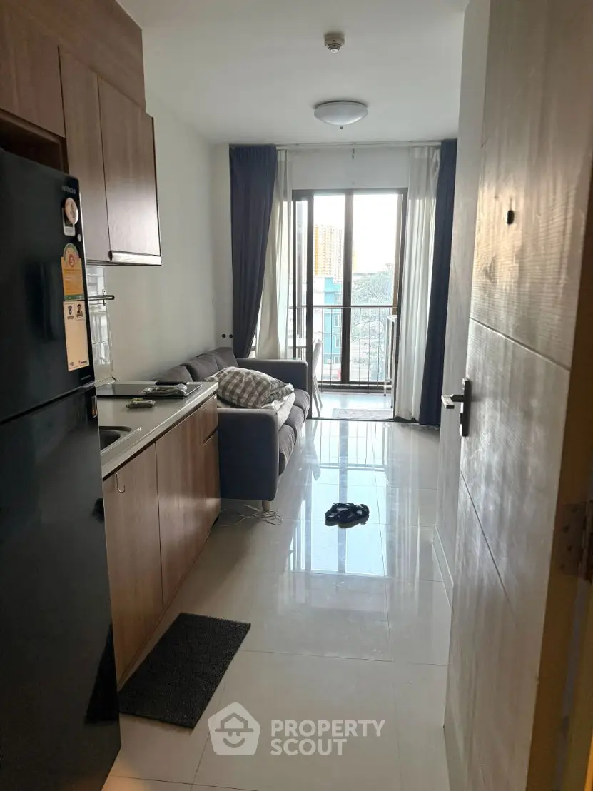 Modern apartment interior with open kitchen and cozy living area leading to a balcony.