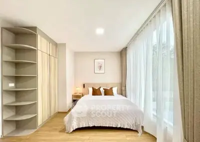 Spacious bedroom with large windows and modern decor, perfect for relaxation and comfort.