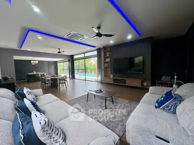 Luxurious open-plan living room with modern decor and pool view, featuring stylish lighting and spacious seating.