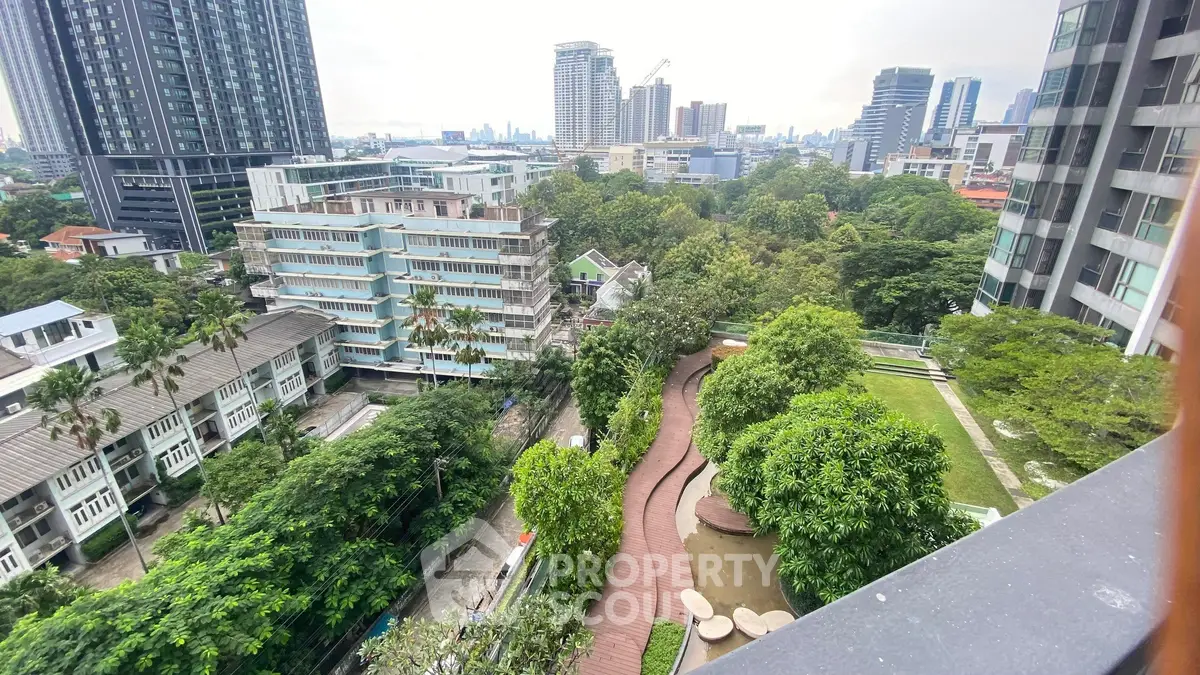 Stunning cityscape view from a high-rise balcony overlooking lush greenery and modern buildings.