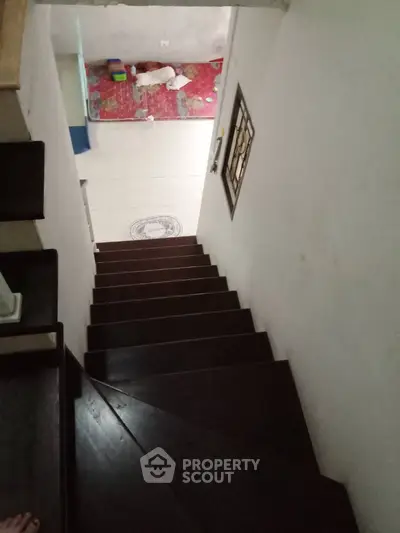 Modern staircase leading to a cozy lower level with tiled flooring and decorative wall art.
