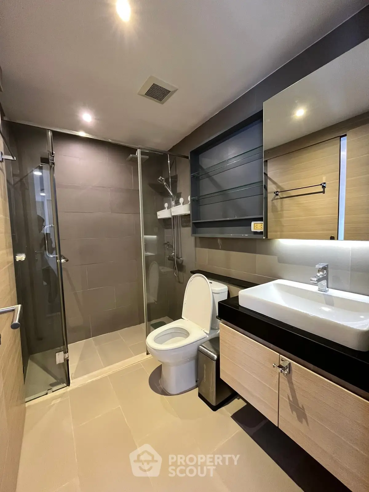 Modern bathroom with glass shower and sleek vanity in contemporary apartment.