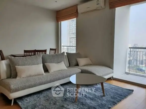 Modern living room with cozy sofa and city view balcony in high-rise apartment.