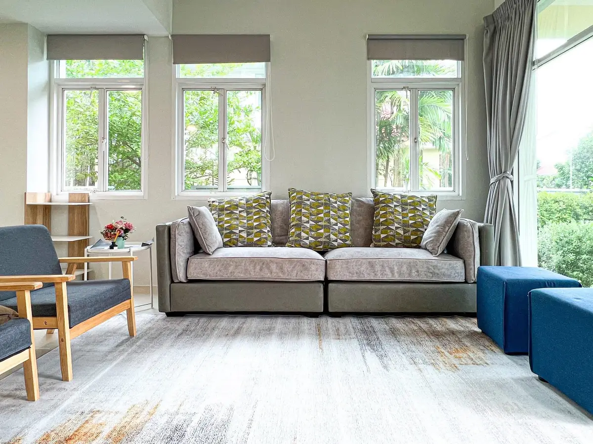 Spacious living room with modern sofa and large windows offering garden view.