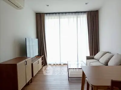 Modern living room with large window, cozy sofa, and sleek TV setup.