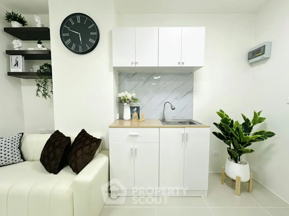 Modern compact kitchen with white cabinets and stylish decor in a cozy living space.