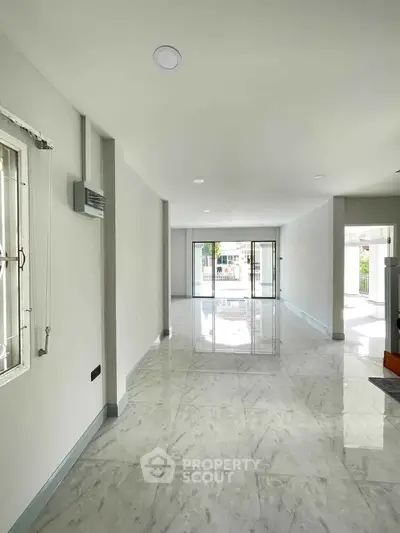 Spacious open-plan living area with marble flooring and large windows for natural light.