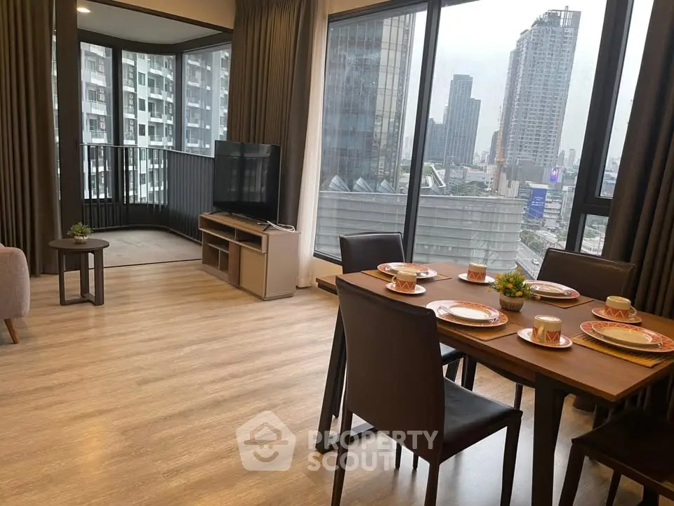 Spacious modern living room with dining area and city view balcony in high-rise apartment.
