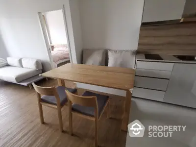 Modern open-layout kitchen with wooden dining table and chairs, adjacent to cozy living area.