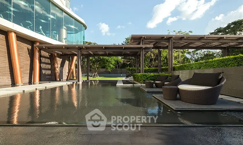 Luxurious outdoor pool area with modern seating and lush greenery, perfect for relaxation and entertainment.