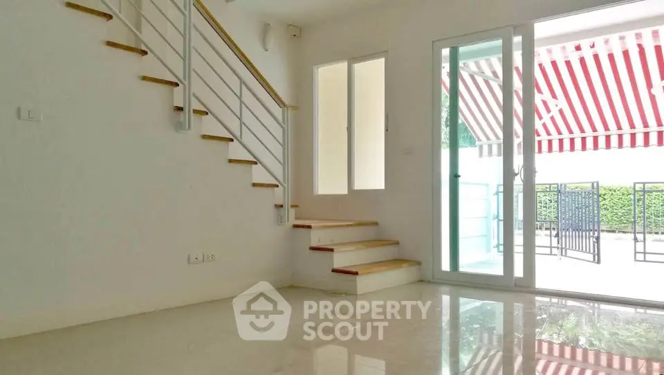 Bright modern living room with staircase and sliding glass doors to patio