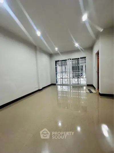 Spacious empty room with glossy tiled floor and large window for natural light.