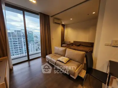 Modern studio apartment with city view and cozy interior design, featuring a comfortable sofa and large windows.
