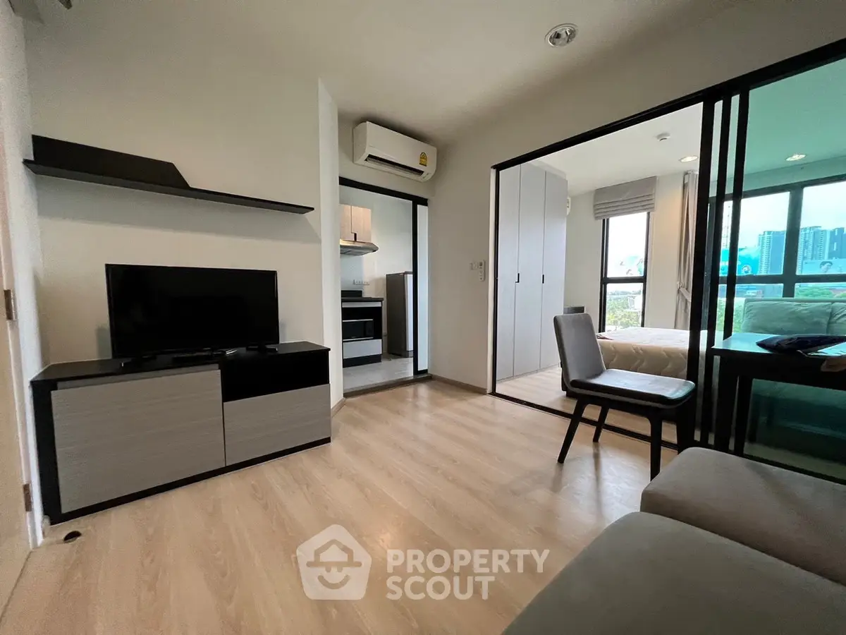 Modern apartment with open living room and bedroom, sleek furniture, and large windows.